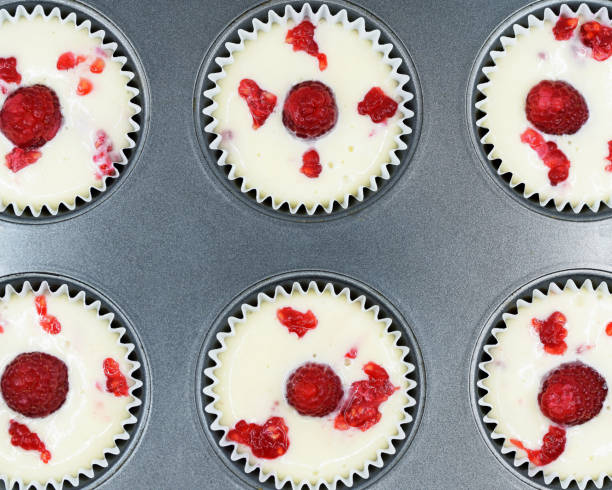 istock Baking tray with muffin paper cases filled with dough, ready to bake 1447969899