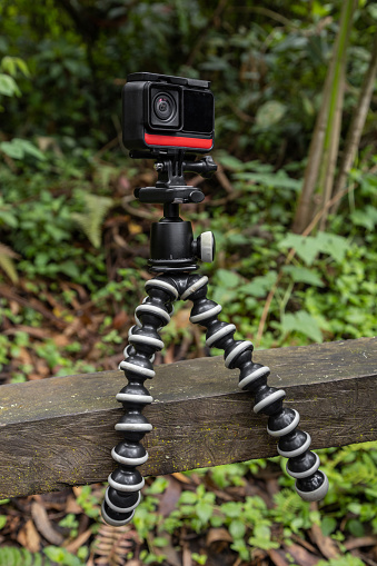 camera on a tripod attached to a wooden railing, nature background, photography hobbies, art technological apparatus