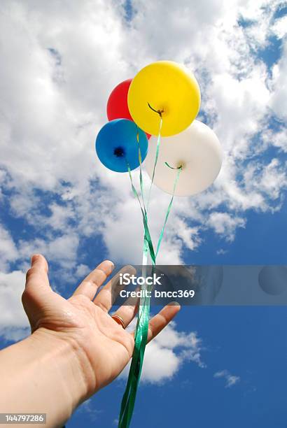 Hand Releasing Four Colorful Balloons Into The Sky Stock Photo - Download Image Now - Releasing, Balloon, Blue
