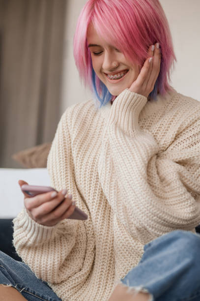 istock Joyful pink-haired girl reading a text message on her smartphone 1447974438