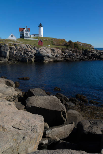 istock Lighthouse on a rock island against a blue sky. 1447977610