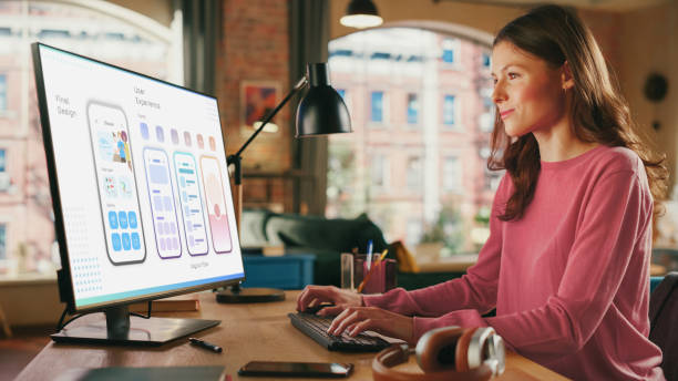 istock Young Beautiful Woman Working on Freelance from Loft Apartment on Desktop Computer. Creative Female Designing Mobile Application User Interface For Fintech Company. Urban City View from Big Window. 1447977762
