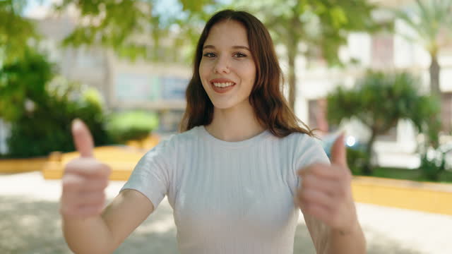 Young woman smiling confident doing ok sign with thumbs up at park