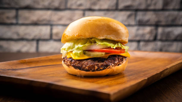 istock classic beef burger include cheese, tomato, onion and patty isolated on wooden board side view on table fast food 1447982446