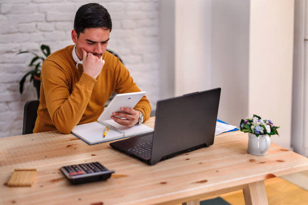 istock A handsome young man is working for a home office during the pandemic time using a tablet. 1447985099