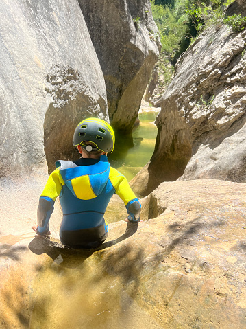Adrenaline sport - Canyoning. Child with neoprene in mountain ravine