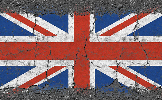 Grunge damaged weathered national flag of UK Great Britain over broken cracked concrete background, symbol of British patriotism