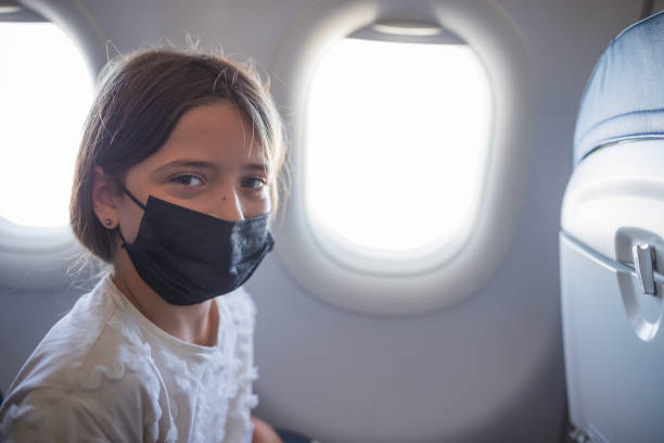istock Cheerful young girl wearing protective mask during airplane flight 1447987759