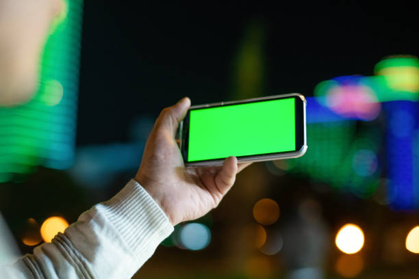istock Excited man holding smartphone outdoors in night city 1447990810