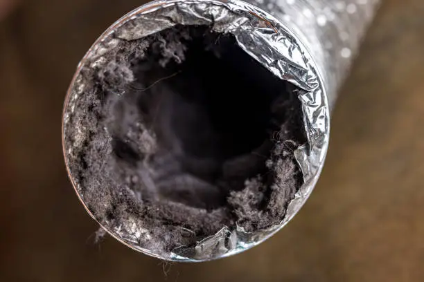 Photo of A dirty laundry flexible aluminum dryer vent duct ductwork filled with lint, dust and dirt