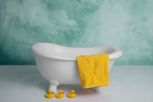 A tiny baby childrens bathtub with a towel and rubber ducks.