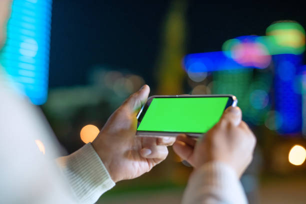 istock Excited man holding smartphone outdoors in night city 1447991073