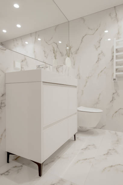 istock Modern minimalist white bathroom interior design with marble style tiles and white taps, vase and wall heater 1447995192