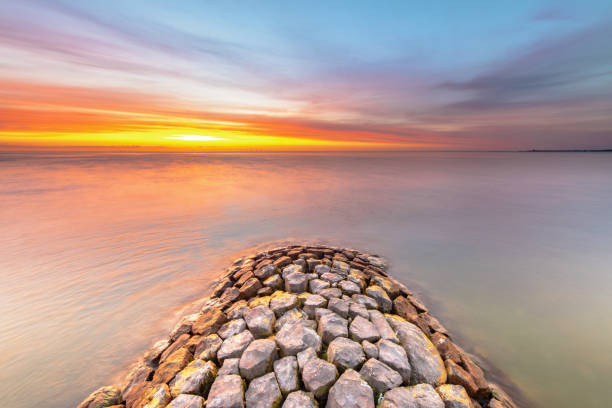 Typical basalt breakwater pier construction at  IJsselmeer near the town of Hindeloopen in the Friesland Province at sunset, Netherlands.