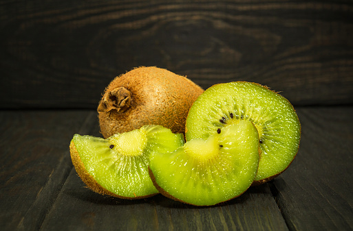 Kiwi and its sliced segments on black vintage table. Idea for a diet