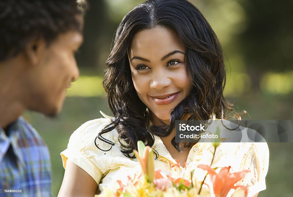 Couple at park. Pretty African American woman holding flower bouquet smiling at man outdoors. African-American Ethnicity Stock Photo