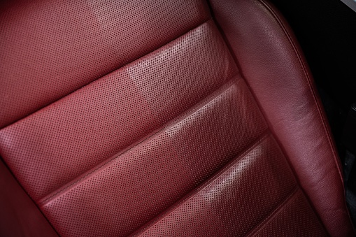 Shallow focus of a textured leather front passenger seat seen in a new car. The car is located at a car dealership.