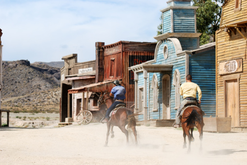 Two cowboys riding away in an old American town