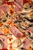 istock Homemade pizza with ham and mushrooms as a background. A close shot of a pizza. Macro photo.Italian pizza capricciosa. Close-up 1448008740