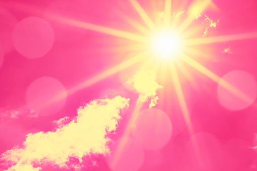 Bright sun with beautiful beams and bokeh lights in the sky. Toned in pink image, space for copy.