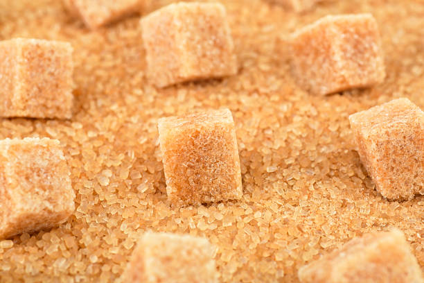 istock Brown sugar cubes on cane sugar crystals, close up. Demerara golden sugar. 1448012425