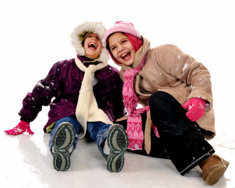 Two elementary girls sitting together and laughing in snow.