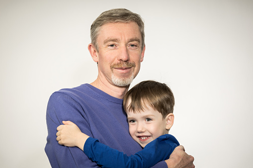 Studio portrait of a 50 year old white man with his 5 year old son  against a white background