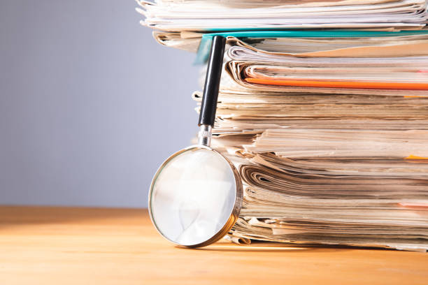 istock Pile of papers and a magnifying glass on the table 1448013862