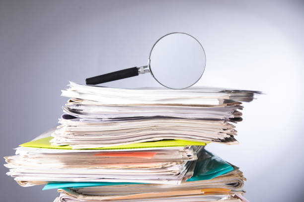 istock Pile of papers and a magnifying glass on the table 1448013863