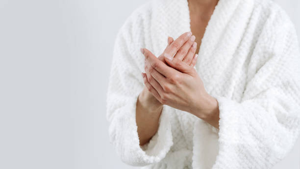 istock Woman in robe applying moisturizer cream on hands 1448014833