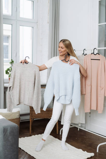 istock Woman with clothes in hands deciding what to put on 1448014851