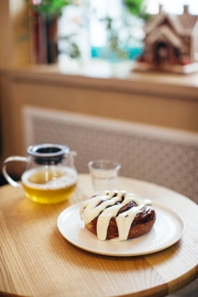 Close up shot of delicious Cinnabon on table with cup of tea and teapot.