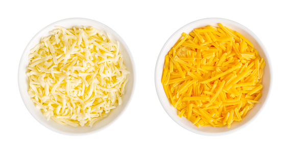 Shredded mozzarella and cheddar cheese, in white bowls. Grated low-moisture mozzarella, and piquant, orange colored natural cheese, both made of pasteurized cow milk. Used for pizza and pasta dishes.