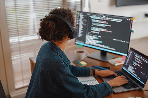 Woman in headphones freelance data scientist work remotely at home. Back view