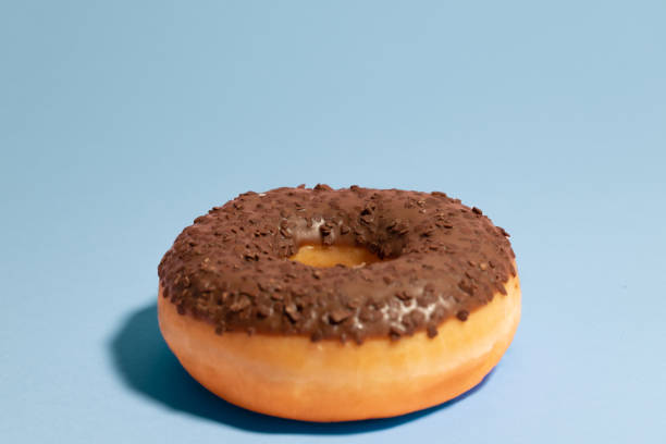 istock Chocolate donut on a blue background. Minimal food concept 1448021360