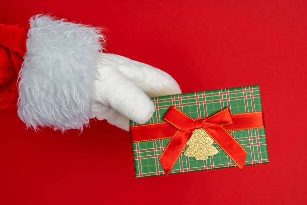 istock Santa's hands are holding a gift for Christmas. red background 1448025363