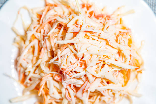 Vegetable salad with sliced fresh tomatoes, cucumbers, onion, young white cabbage with mayonnaise dressing on brown dish on a gray background