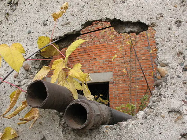 Two water-pipes stick out from a hole in a thin concrete.