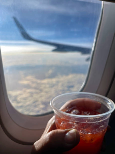 istock Airplane passenger with drink in hand looking out the window 1448029688