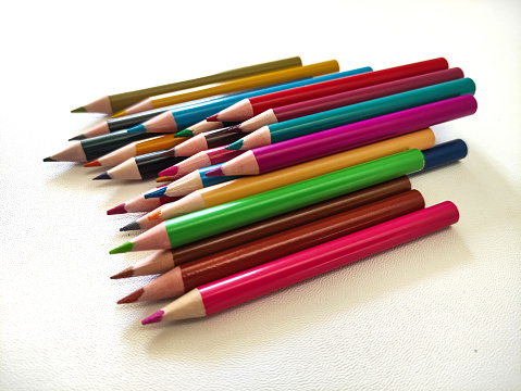 Various colored pencils on top of a white sheet with copyspace
