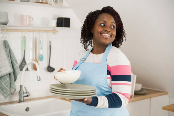 istock Happy Afro woman arranging washed plates at her kitchen 1448036062