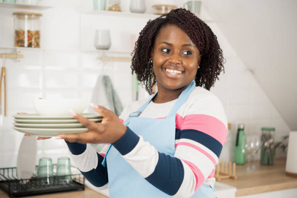 istock Happy Afro woman drying washed dishes at her kitchen 1448036063