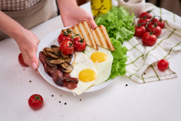 istock Fried eggs, bacon, tomato and toasted bread in white ceramic plate 1448036071