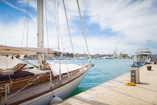 Moored white yachts, sport and sailboats. Scenic landscape background. Holiday rest during summer evening. Dream vacation cruise. Parked nautical vessels. Mirror surface of river. European leisure.