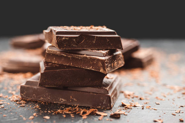 istock Dark chocolate bar pieces on dark background with copy-space, grated chocolate and spices, pile chunks of broken chocolate 1448038378