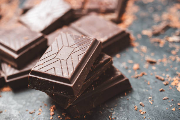 istock Dark chocolate bar pieces on dark background with grated chocolate, pile chunks of broken chocolate 1448038401