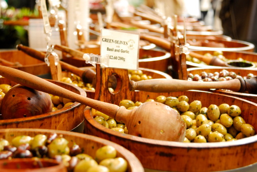 A selection of olives for sale in wooden buckets.
