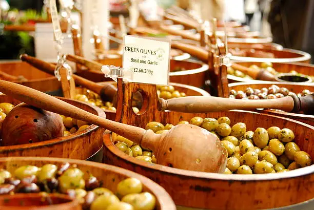 A selection of olives for sale in wooden buckets.