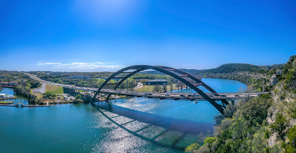 Austin, Texas- Through arch bridge over the Colorado River. Vehicles passing on the large bridge against the view of buildings and clear sky background.