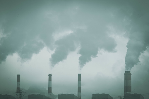 Cropped shot of coal power plant with steam pouring out of the stack. Industrial smoke stack of coal power plant in the morning.